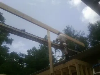 Carpenter setting a ridge beam over a new addition frame — Ice Dam Removal by Roofing Brothers in Conehatta