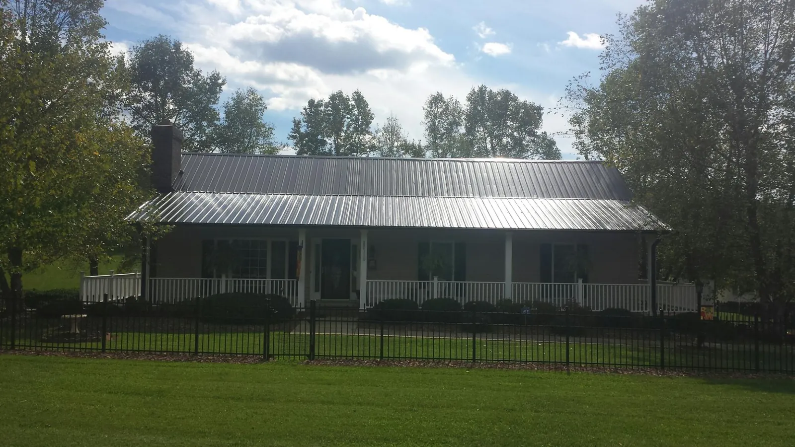 Gray metal roof on a brick ranch with a full width front porch — Gutter Guard Installation work by our crew in Conehatta